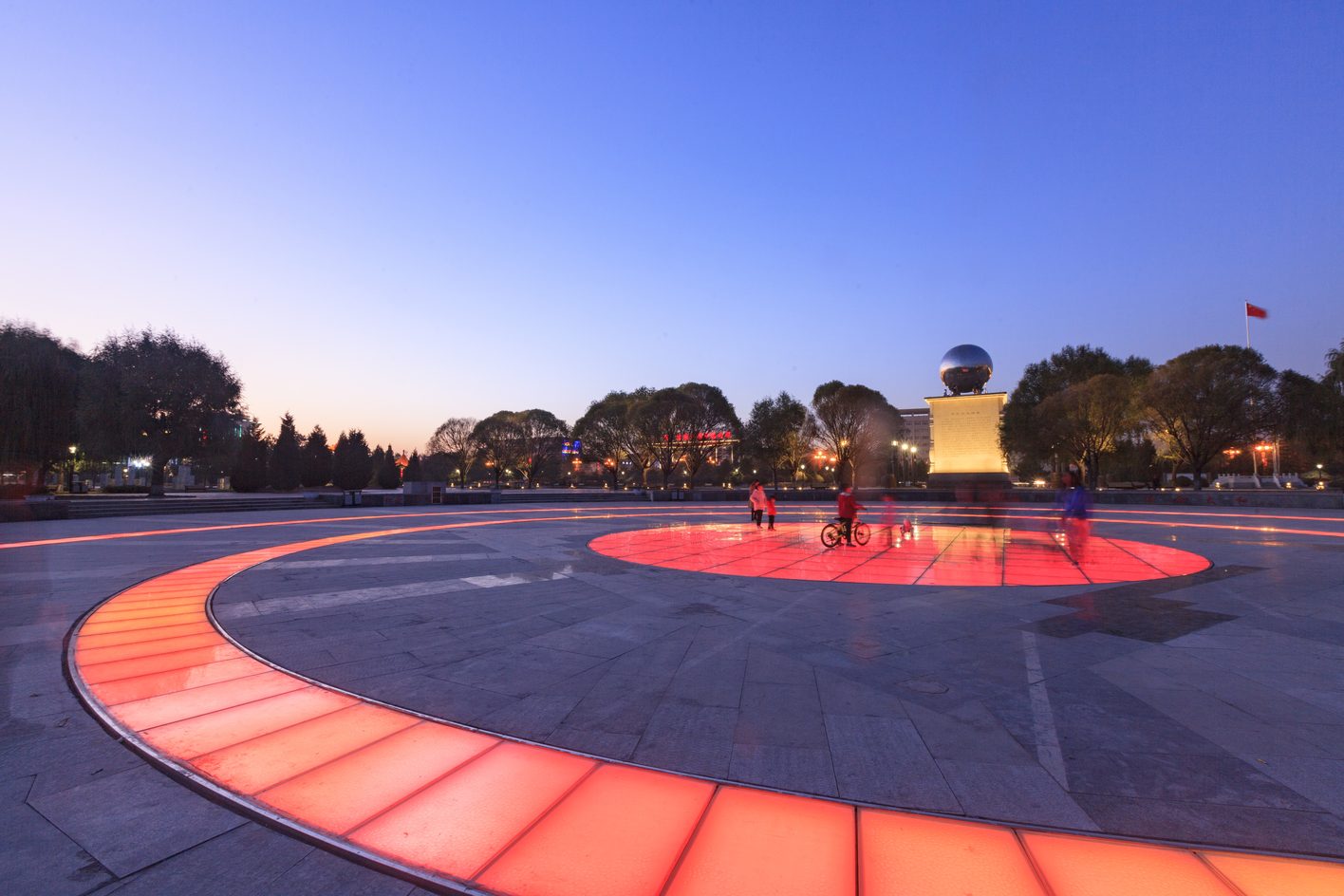 Pinglu project completed: a plaza at dusk, the central sculpture accented, a ring of red in-ground light for guidance, the rest of the ground kept low